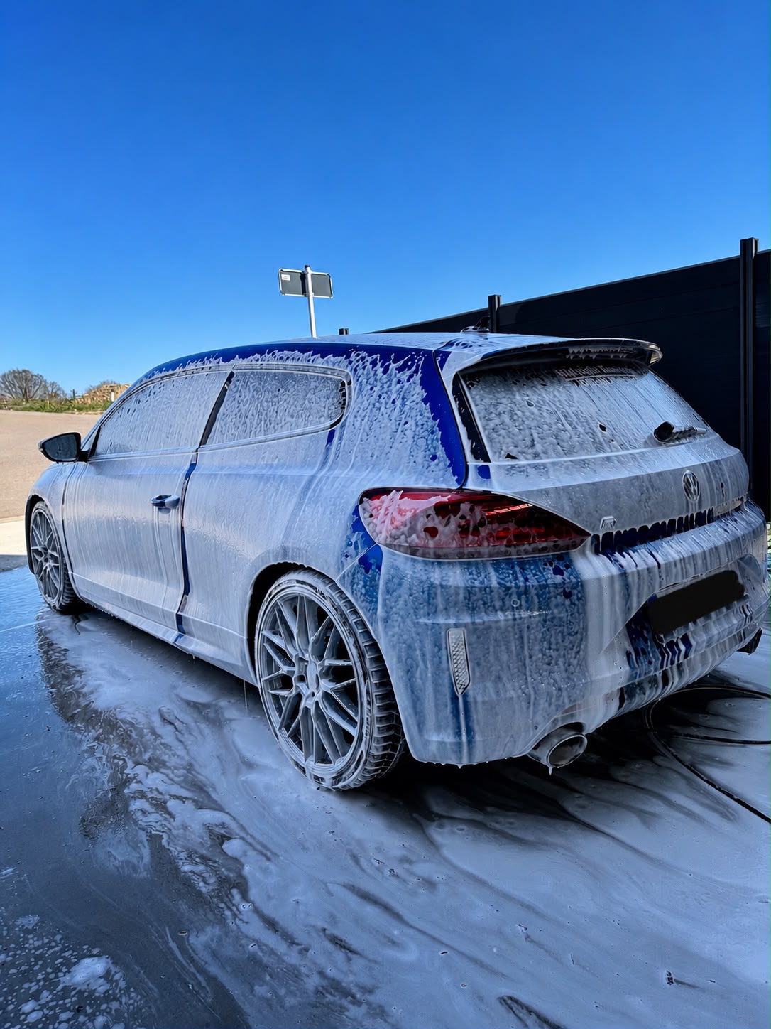 Volkswagen Scirocco bleue recouverte de mousse active pendant un prélavage